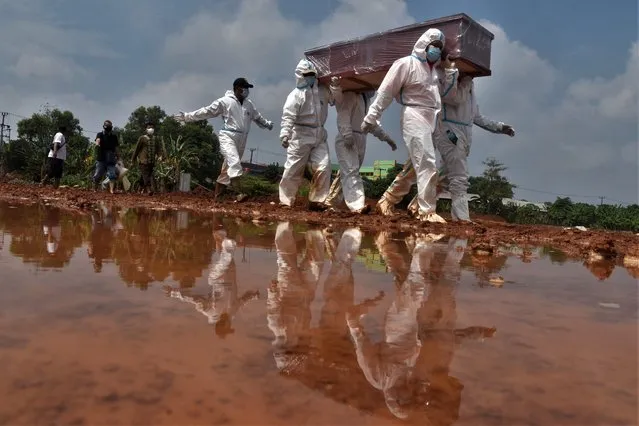 Grave diggers carry the coffin of a victim who died from Covid-19 coronavirus for burial at a cemetery in Bekasi, Indonesia on August 10, 2021. (Photo by Rezas/AFP Photo)