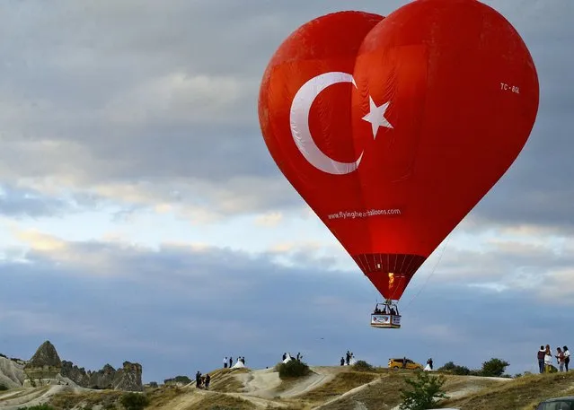 A heart shaped hot air balloon with the Turkish flag on one side glides at the historical Cappadocia region, located in Central Anatolia's Nevsehir province, Turkey on July 7, 2021. (Photo by Ismail Duru/Anadolu Agency via Getty Images)