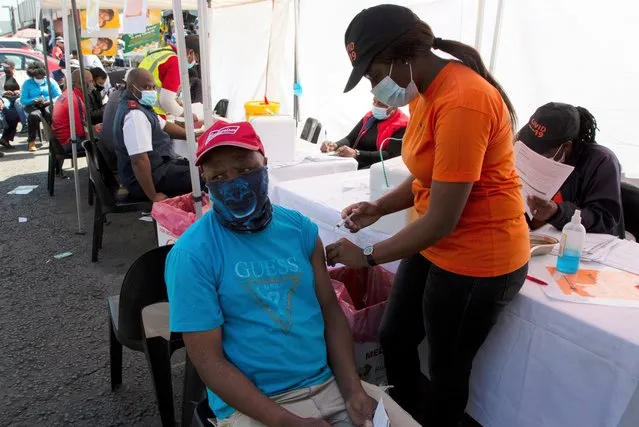 A patient receives a Johnson & Johnson vaccine at a pop-up vaccination centre, at the Bare taxi rank in Soweto, South Africa, Friday, August 20, 2021. Faced with slowing numbers of people getting COVID-19 jabs, South Africa has opened eligibility to all adults to step up the volume of inoculations as it battles a surge in the disease driven by the delta variant. (Photo by Denis Farrell/AP Photo)
