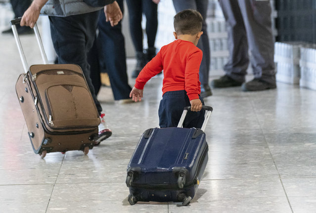 A young boy pulls a suitcase as refugees arrive from Afghanistan aboard an evacuation flight at Heathrow Airport in London, Thursday August 26, 2021. The U.K. defense ministry has organised an air-lift of vulnerable citizens from Kabul, following the Taliban assuming power in Afghanistan. (Photo by Dominic Lipinski/Pool via AP Photo)