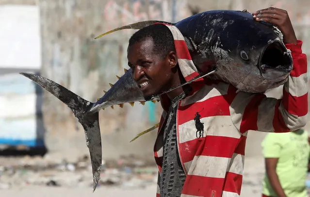 A Somali man carries a fish at Liido beach in Mogadishu, Somalia on December 29, 2023. (Photo by Feisal Omar/Reuters)