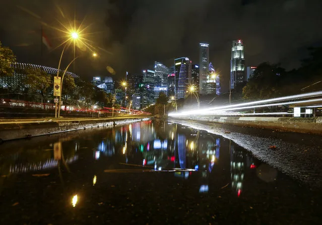 A longtime exposure of the financial district reflected in a puddleas cars drive along the Esplanade bridge in Singapore, February 6, 2016 night. (Photo by Wallace Woon/EPA)