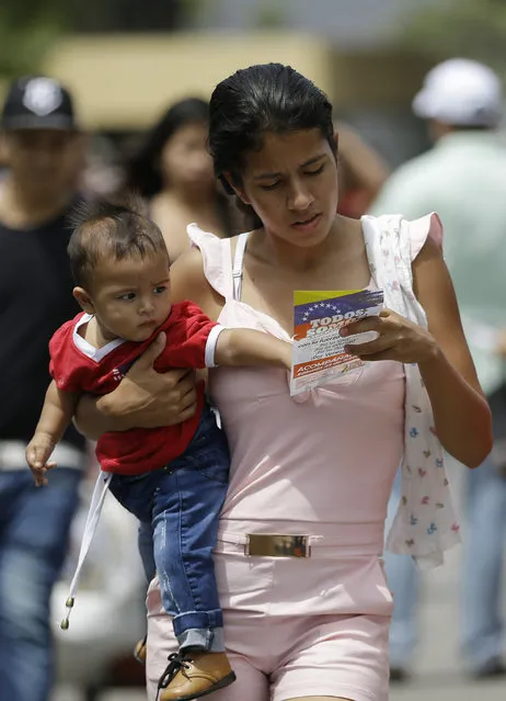 A Venezuelan woman with a baby reads a flyer, given to her by Venezuelan politicians in exile, inviting people to come out to the streets on Feb. 23 to support the planned aid delivery to Venezuela, in La Parada, on the border with Venezuela, Colombia, Sunday, February 17, 2019. As part of U.S. humanitarian aid to Venezuela, Sen. Marco Rubio, R-Fla, is visiting the area where the medical supplies, medicine and food aid is stored before it it expected to be taken across the border on Feb. 23. (Photo by Fernando Vergara/AP Photo)