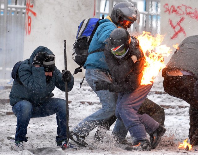 Protesters clash with the police in the center of Kiev on January 22, 2014. Ukrainian police on Wednesday stormed protesters' barricades in Kiev as violent clashes erupted and activists said that one person had been shot dead by the security forces. Total of two activists shot dead during clashing. The move by police increased tensions to a new peak after two months of protests over President Viktor Yanukovych's failure to sign a deal for closer ties with the EU. (Photo by Sergei Supinsky/AFP Photo)