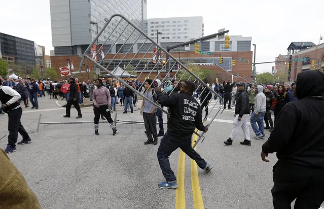 A protestor throws a barricade at a bar near Oriole Park at Camden Yards after a rally for Freddie Gray, Saturday, April 25, 2015, in Baltimore. (Photo by Patrick Semansky/AP Photo)