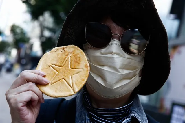A woman wearing a face mask shows a Korean-style sugar candy “dalgona” in Seoul, South Korea, 14 October 2021. Dalgona candy which is made by melting sugar and frothing up with a pinch of baking soda, is rapidly gaining popularity around the world after it was prominently featured in the mega-hit Netflix series “Squid Game”. (Photo byJeon Heon-Kyun /EPA/EFE)