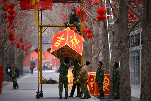 Chinese workers hang a lantern for the upcoming Lunar New Year at a park in Beijing on January 24, 2014. (Photo by Wang Zhao/AFP Photo)