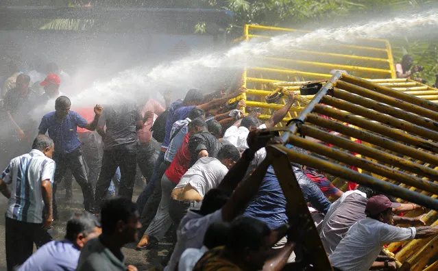 Sri Lankan port workers backed by the Marxist political party, attempt to topple a barricade as police fire water cannon during a protest march near the presidential secretariat in Colombo, Sri Lanka, Wednesday, February 1, 2017. The protest was against the alleged privatization plans of the port by the government. (Photo by Eranga Jayawardena/AP Photo)