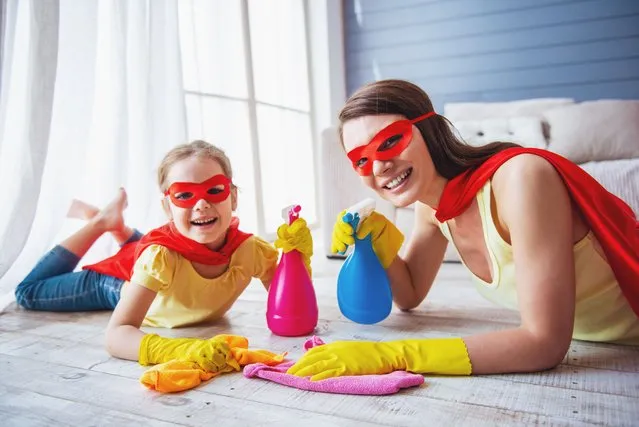 Beautiful mother and her cute little daughter dressed like superheroes are holding sprayer, looking at camera and smiling while cleaning the house. (Photo by George Rudy/Getty Images)