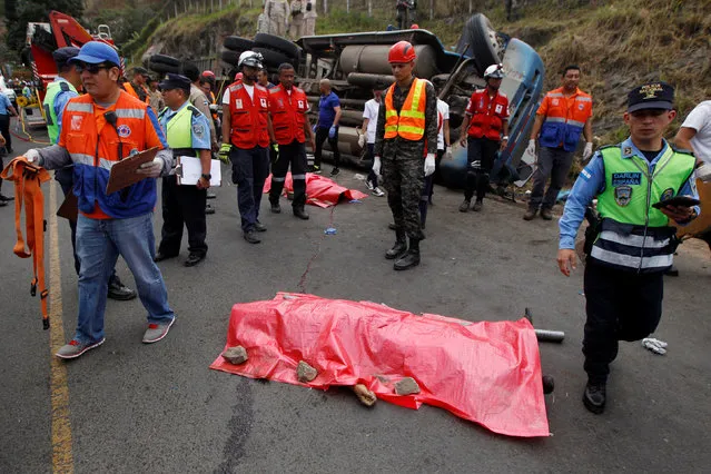 Rescue workers and members of the Red Cross stand next to a dead body after a crash between a bus and a truck on the outskirts of Tegucigalpa, Honduras, February 5, 2017. (Photo by Jorge Cabrera/Reuters)