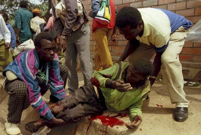 Friends and relatives lift a man wounded by a mortar fired by Rwanda Patriotic Front at a downtown government held area in Kigali July 1, 1994. The RPF seized control of Rwanda after driving the 40,000-strong Hutu army and more than 2 million civilian Hutus into exile in Burundi, Tanzania and the former Zaire, now Democratic Republic of Congo. (Photo by Corinne Dufka/Reuters)