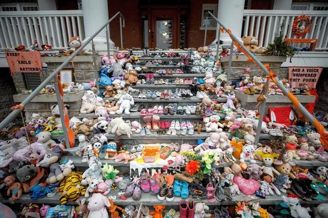 Children shoes and stuffed animals sit on the steps as a tribute to the missing children of the former Mohawk Institute Residential School, in Brantford, Canada, November 9, 2021. Community members and survivors gathered on Tuesday at the former residential school as the search for remains begins. (Photo by Cole Burston/AFP Photo)