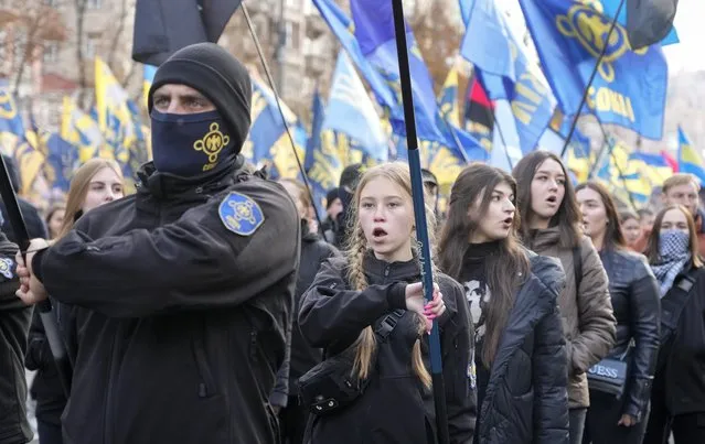 Members of nationalist movements chant and march during a rally marking Defender of Ukraine Day, in center Kyiv, Ukraine, Thursday, October 14, 2021. Some 15,000 far-right and nationalist activists marched in the Ukrainian capital, chanting “Glory to Ukraine” and waving yellow and blue flags. (Photo by Efrem Lukatsky/AP Photo)