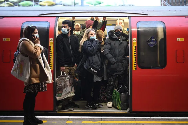 Commuters with and without face coverings ride a tube train at Stratford underground station in east London on December 1, 2021. Britain will require all arriving passengers to isolate until they can show a negative PCR test against Covid-19 and is restoring a mandate to wear face masks in shops and public transport as part of its response to the new Omicron strain of Covid-19. (Photo by Daniel Leal/AFP Photo)