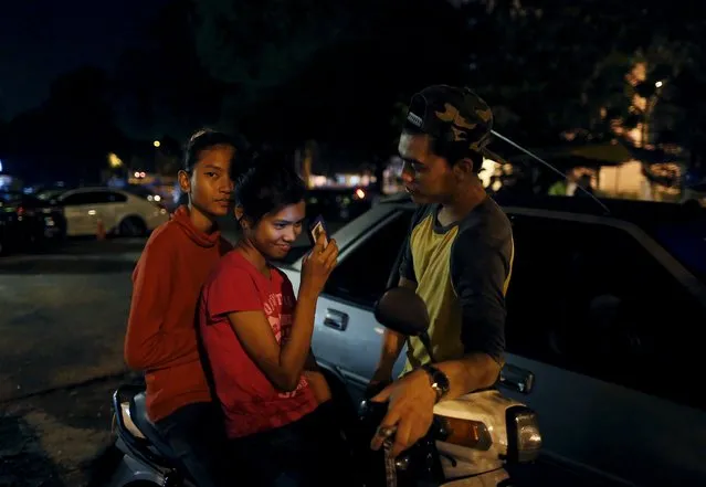 A motorcyclist chats to young women gathered to watch the motorbike racing on a highway in Kuala Lumpur, Malaysia, July 26, 2015. (Photo by Olivia Harris/Reuters)