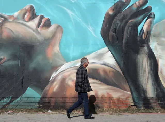 A man walks past an artwork by German artist Norm Abartig (@norm_abartig) and South African artist Nicholas Kerr aka Dekor One (@dekor) as part of the Westdene Graffiti Project in downtown Johannesburg, South Africa, 31 May 2019. The Westdene Graffiti Project has helped raise awareness of the art form of graffiti in the area. The art form has flourished in the inner city as the area has decayed over the past decade. Various artists from both South Africa and the rest of the world have taken their spray cans to the huge walls in South Africa's biggest city. (Photo by Kim Ludbrook/EPA/EFE)