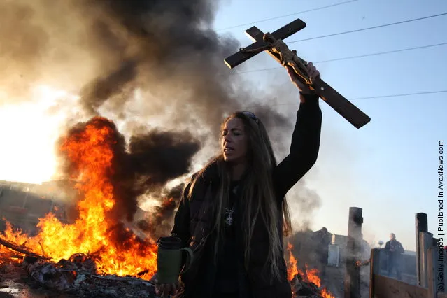 An activist holds up a crucifix as a barricade burns during evictions from Dale Farm travellers camp