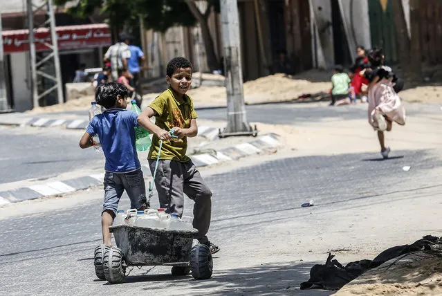 A Palestinian child pulls a cart loaded with jerricans filled with drinking water from public taps in Khan Yunis in the southern Gaza strip on July 10, 2019. The population of Gaza facing a drinking water problem is increasing. Lacking natural resources, the Gaza Strip suffers from a chronic shortage of water, electricity and petrol. More than two-thirds of the population depends on humanitarian aid, which the United Nations says could become uninhabitable by 2020. (Photo by Said Khatib/AFP Photo)