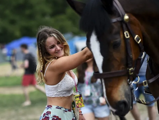 A reveller pats a police horse as they chat with officers during the Glastonbury Festival at Worthy Farm in Somerset, Britain, June 25, 2015. (Photo by Dylan Martinez/Reuters)