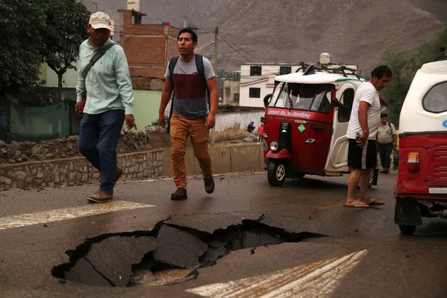 People walk after a landslide and flood in Chosica, east of Lima, Peru on March 17, 2017. (Photo by Guadalupe Pardo/Reuters)