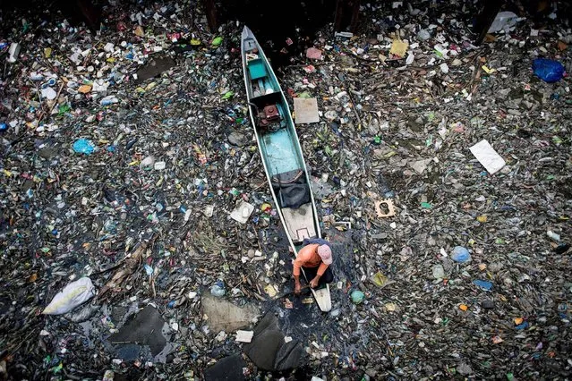 A worker collects garbage from the Marilao River in Bulacan, north of Manila, on March 18, 2017. Pure Earth, formerly known as the Blacksmith Institute, a non-governmental organisation that works to solve pollution problems in the developing world, named Marilao River as one of the 30 dirtiest places in the world in 2007. (Photo by Noel Celis/AFP Photo)