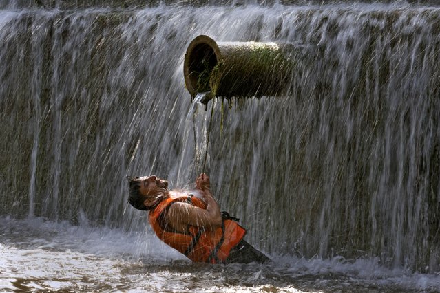 A Pakistani man cools himself off in a stream as temperatures reached 39 Celsius (102.2 Fahrenheit) in Islamabad, Pakistan, Friday, May, 24, 2024. Many cities in Pakistan are facing heat wave conditions with temperatures reaching nearly 50 Celsius (122 Fahrenheit in some places. (Photo by Anjum Naveed/AP Photo)