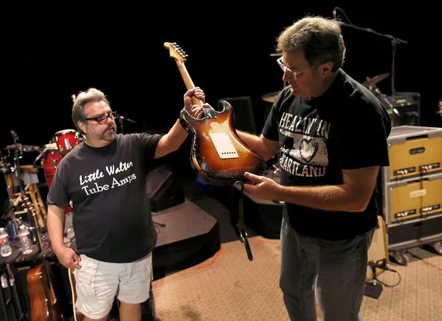 Guitar technician Vinnie Garcia hands Country legend Vince Gill his 1957 Fender Stratocaster after a sound check at the Mesa Performing Arts Center, in Mesa, Ariz. on Thursday, October 24, 2013. Garcia, who has been best friends with Gill since the seventh grade, sold Gill his first Stratocaster for $200 and a pair of cowboy boots. Gill says, “I love the versatility of the guitar as much as anything, no matter what way you want to try to play it, it always responds”. (Photo by Matt York/AP Photo)