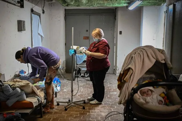A nurse checks a baby being treated at a pediatrics center after unit was moved to the basement of the hospital which is being used as a bomb shelter, in Kyiv on February 28, 2022. The Russian army said on February 28, 2022, that Ukrainian civilians could “freely” leave the country's capital Kyiv and claimed its airforce dominated Ukraine's skies as its invasion entered a fifth day. (Photo by Aris Messinis/AFP Photo)