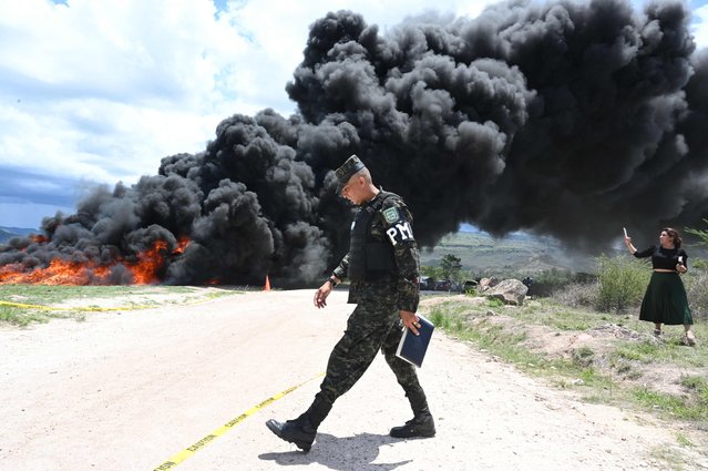 An Honduran Military Police of Public Order officer walks next to the fire during the incineration of 5.6 tonnes of cocaine in a military unit on the southern outskirts of Tegucigalpa on June 13, 2024. This is the second cocaine-burning operation in Honduras in 2024. On April 9, 1,350 kilos were confiscated and burned two weeks earlier by ten Hondurans detained on two boats in the jurisdiction of the insular department of Islas de la Bahia (Caribbean). (Photo by Orlando Sierra/AFP Photo)