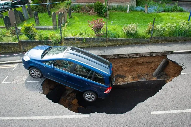 A car which has partially disappeared down a sinkhole in Woodland Terrace in Greenwich, south-east London Thursday May 12, 2016. (Photo by Dominic Lipinski/PA Wire via AP Photo)