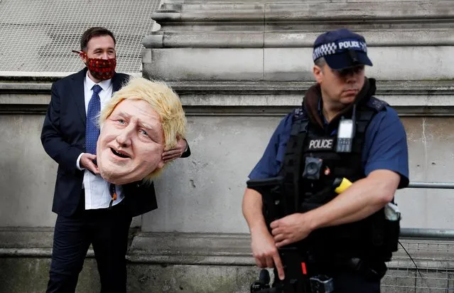 A Greenpeace activist carries a model head depicting Britain's Prime Minister Boris Johnson outside Downing Street in London, Britain, July 13, 2021. (Photo by Peter Nicholls/Reuters)