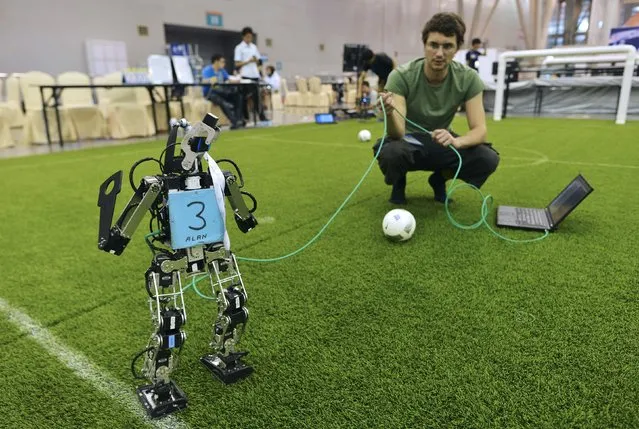 A participant tests a robot soccer player as he prepares for the upcoming RoboCup 2015, at an exhibition centre in Hefei, Anhui province, China, July 18, 2015. (Photo by Reuters/Stringer)