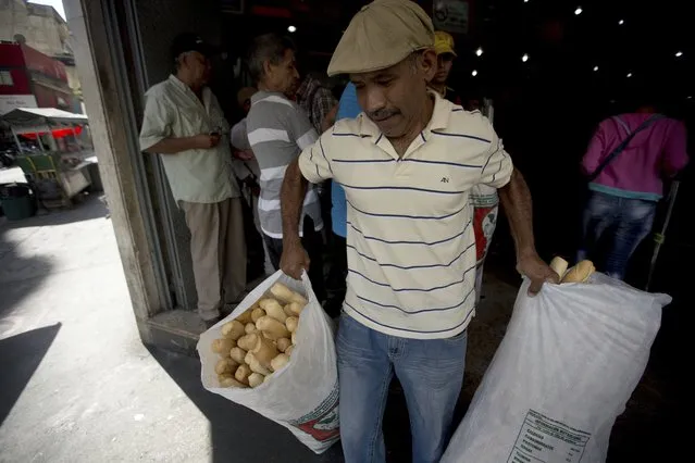 In this March 17, 2017 photo, an employee of the Minka state-run bakery carries bags of bread to be distributed to state-run grocery stores in Caracas, Venezuela. Agents from the National Superintendent of Fair Prices raided Mansion’s Bakery last week and accused the owners of hoarding scarce sacks of government-imported flour, saying the subsidized goods should have been used to make price-regulated loaves but instead was turned into more expensive croissants and sweet rolls. (Photo by Fernando Llano/AP Photo)