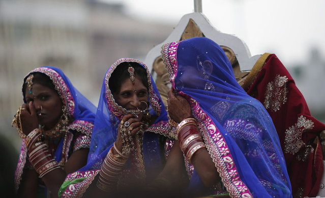 Brides arrive in a horse cart to attend a mass wedding ceremony at Ramlila ground in New Delhi June 15, 2014. A total of 92 physically challenged couples of all religions from across India took their wedding vows on Sunday during the mass wedding ceremony organised by a non-governmental organisation (NGO), organisers said. (Photo by Adnan Abidi/Reuters)