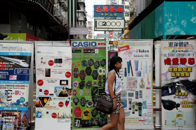 A woman walks past advertisements from nearby retail shops at Mongkok shopping district in Hong Kong, China, May 31, 2016. (Photo by Bobby Yip/Reuters)