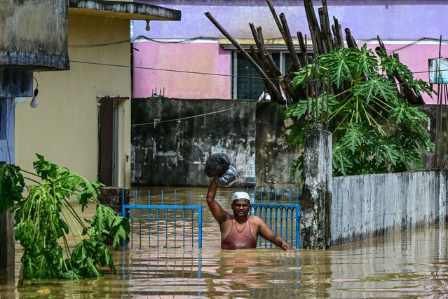 A man carrying his belongings wades through flood waters in Feni, in south-eastern Bangladesh, on August 23, 2024. Flash floods wrought havoc in Bangladesh on August 23 as the country recovers from weeks of political upheaval, with the death toll rising to 13 and millions more caught in the deluge. (Photo by Munir Uz Zaman/AFP Photo)