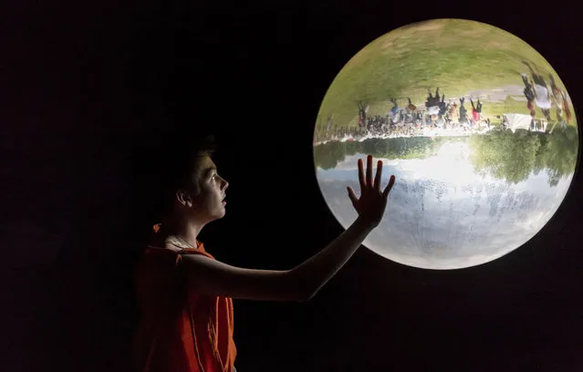 A boy looks at a glass bowl showing the outside upside down in a museum in Bramsche-Kalkriese, Germany, Sunday, June 4, 2017. (Photo by Guido Kirchner/DPA via AP Photo)