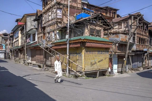 Kashmiri man carry a bamboo ladder as he walks past closed market during a strike against the remarks made by Nupur Sharma, a spokesperson of governing Hindu nationalist party about Prophet Mohammed, in Srinagar, Indian controlled Kashmir, Friday, June 10, 2022. In Indian-controlled Kashmir, authorities locked down two towns on Friday and snapped internet on mobile phones in several towns and in Srinagar, the disputed region’s main city, fearing anger against the insulting remarks to Islam could morph into larger, anti-India protests. (Photo by Dar Yasin/AP Photo)