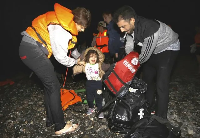 Syrian refugees dress-up their child with dry clothes moments after arriving at a beach on the Greek island of Kos after crossing a part of the Aegean sea from Turkey to Greece on a dinghy August 13, 2015. (Photo by Yannis Behrakis/Reuters)