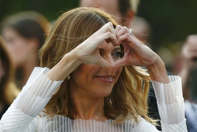 Julie Snyder, the bride of Parti Quebecois leader Pierre Karl Peladeau, makes a heart with her hands as she arrives at her wedding at the Musee de l'Amerique Francophone in Quebec City, August 15, 2015. (Photo by Mathieu Belanger/Reuters)