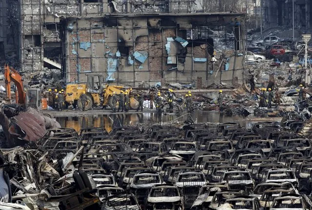 Rescue workers stand near damaged cars and buildings close to the site of last week's explosions at Binhai new district in Tianjin, China, August 17, 2015. Many operations have resumed at China's Tianjin port, trade sources said, after explosions last week that killed more than 100 people and disrupted business at what is an important oil, gas and bulk import harbor for Asia's biggest economy. (Photo by Kim Kyung-Hoon/Reuters)