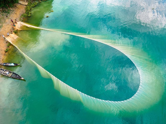 An aerial view shows local tribal people fishing with boats and large colorful nets in Kaptai Lake in Rangamati, Bangladesh, on October 22, 2024. (Photo by Muhammad Amdad Hossain/NurPhoto/Rex Features/Shutterstock)