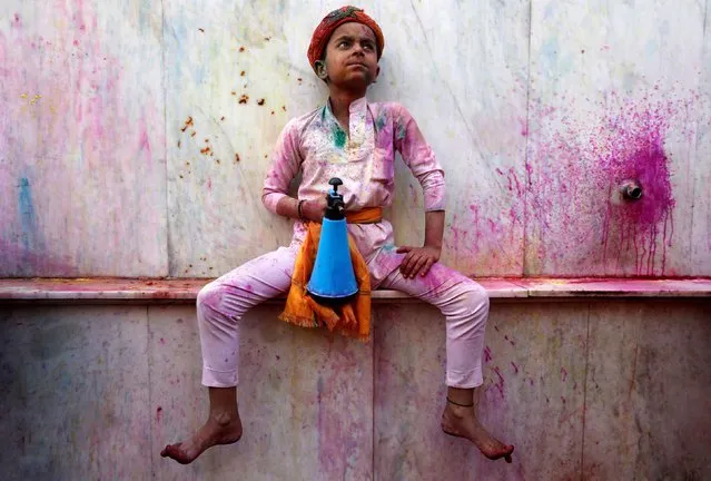 A boy holds a spray bottle as he takes part in the religious festival of Holi inside a temple in Nandgaon village, in the state of Uttar Pradesh, India, March 5, 2020. (Photo by Adnan Abidi/Reuters)