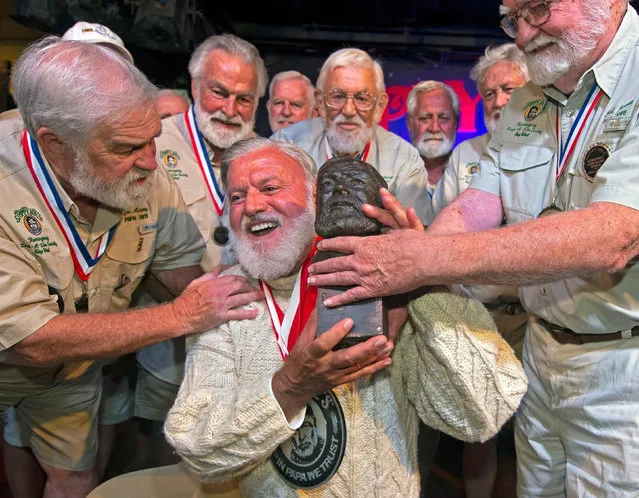Jon Auvil, reacts as he receives congratulatory smooches from Joe Maxey, the 2019 winner, and Fred Johnson,who won in 1986 after winning the 2022 Hemingway Look-Alike Contest, at Sloppy Joe's Bar in Key West, FL, U.S. July 23, 2022. Hemingway lived and wrote in Key West during most of the 1930s. (Photo by Andy Newman/Florida Keys News Bureau/Handout via Reuters)
