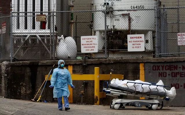 A medical professional stands with a body on a hospital gurney as it is moved to be temporarily stored in a mobile morgue, put in place due to lack of space at the hospital, outside of the Brooklyn Hospital Center in Brooklyn, New York, USA, on 30 March 2020. New York City is still the epicenter of the coronavirus outbreak in the United States and as of Monday there were reportedly 1,218 people who have died as a result of complications from COVID-19. (Photo by Justin Lane/EPA/EFE/Rex Features/Shutterstock)