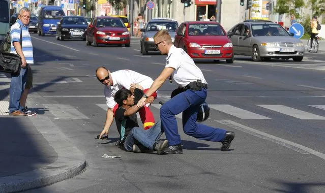 Hungarian police officers detain a migrant in the middle of a street in Budapest, Hungary September 2, 2015. (Photo by Laszlo Balogh/Reuters)