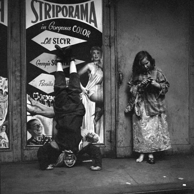 This 1953 photo provided by the Estate of Vivian Maier and John Maloof Collection shows a man doing a headstand in front of a poster advertising a strip show in New York. (Photo by Vivian Maier/Estate of Vivian Maier and John Maloof Collection via AP Photo)