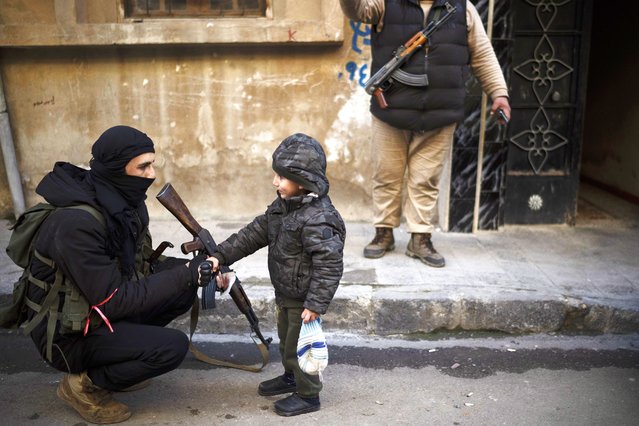 A member of the new security forces shakes hands with a boy during an operation to detain men suspected of being part of militias or loyalist soldiers of the ousted president Bashar Assad in Homs, Syria, Friday, January 3, 2025. (Photo by Leo Correa/AP Photo)