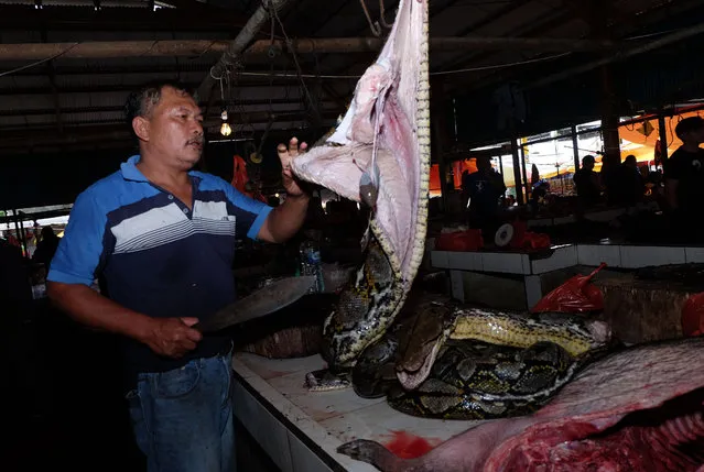 This photo taken on February 8, 2020 shows a vendor slicing up a large snake at the Tomohon Extreme Meat market on Sulawesi island, as business is booming and curious tourists keep arriving to check out exotic fare that enrages animal rights activists. (Photo by Ronny Adolof Buol/AFP Photo)