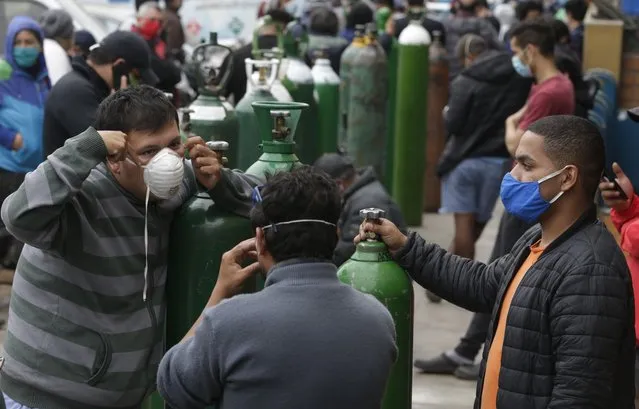 People wearing masks to prevent the spread of the new coronavirus stands in line to refill their empty oxygen cylinders in Callao, Peru, Wednesday 3, 2020. Long neglected hospitals in Peru and other parts of Latin America are reporting shortages of Oxygen as they confront the COVID-19 pandemic. (Photo by Martin Mejia/AP Photo)
